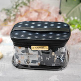 کیف آرایشی زنانه شفاف با درب مشکی و لوگوی طلایی Chanel، حاوی حولههای طرحدار با لوگوی شنل، مناسب برای استفاده روزمره یا هدیه لوکس