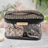 کیف آرایشی زنانه شفاف با لبه مشکی و یراق طلایی، دارای لوگوی Louis Vuitton و محتویات با طرح مونوگرام کلاسیک در رنگهای متنوع