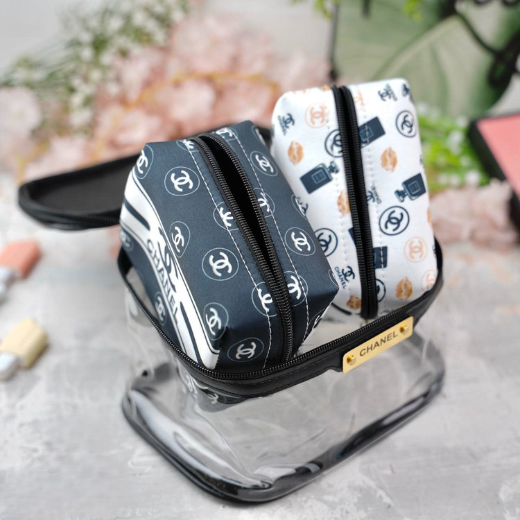 کیف آرایشی زنانه شفاف با زیپ مشکی و پلاک طلایی، شامل دو کیف داخلی با طرح لوگوی Chanel و گرافیکهای آرایشی، مناسب برای نگهداری لوازم آرایشی در سفر یا استفاده روزمره