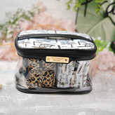 کیف آرایشی زنانه شفاف با پایه مشکی و زیپ مشکی، دارای پلاک طلایی Victoria's Secret و محتویات شامل لباسزیر با طرح پلنگی و نوشتهدار، مناسب برای هدیه یا استفاده روزمره