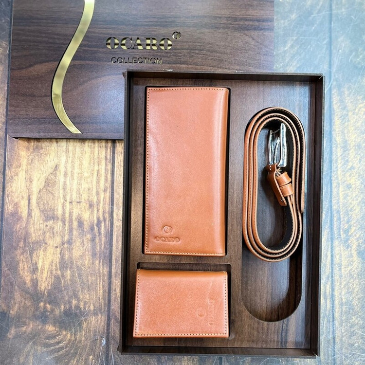 ست هدیه چرمی طبیعی رنگ عسلی شامل کمربند، کیف پول و جا کارتی، چیدمانشده در جعبه چوبی با ظاهر گرم و کلاسیک