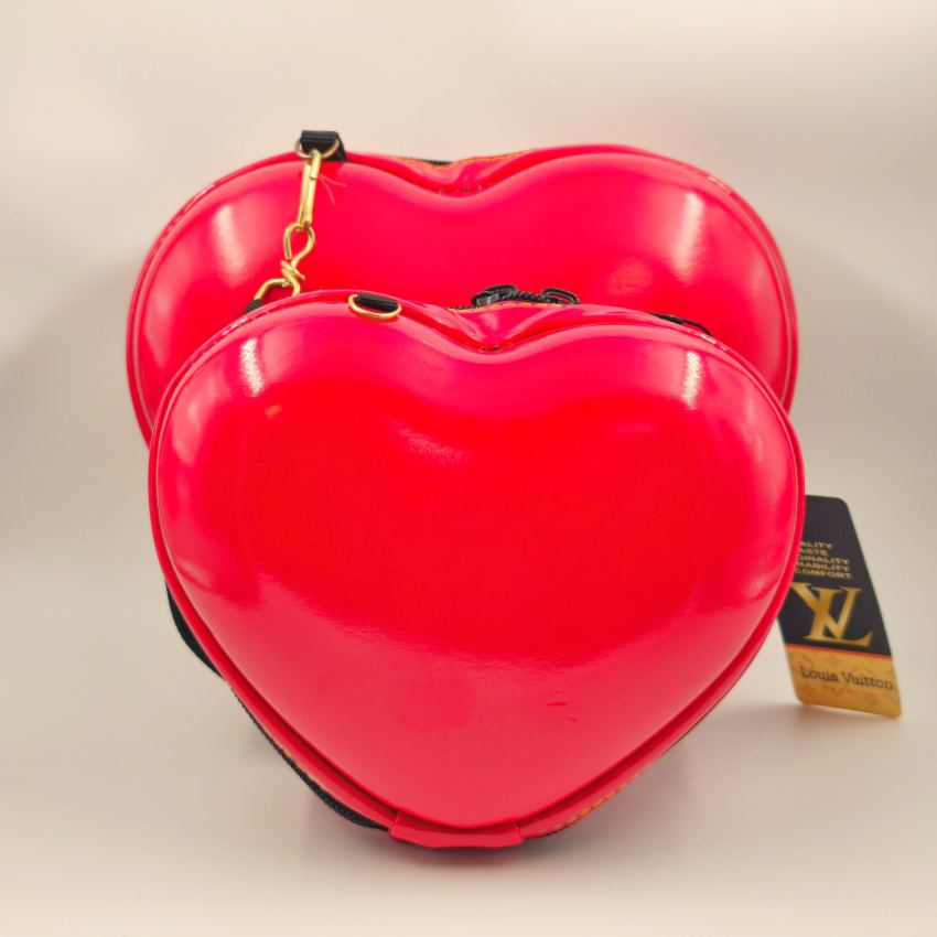 کیف آرایشی قلبی در دو سایز بزرگ و کوچک، با طراحی قالبی قرمز براق و بند قابل جدا شدن، چیده‌شده کنار هم برای نمایش تفاوت ابعاد