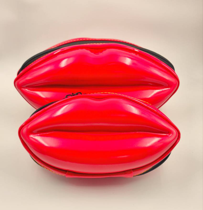 کیف آرایشی لب‌شکل در دو سایز بزرگ و کوچک، با طراحی قالبی قرمز براق و فضای داخلی مشبک، چیده‌شده کنار هم برای نمایش تفاوت ابعاد