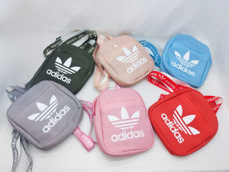 بادی بگ آدیداس با لوگوی سفید، بند برنددار و رنگبندی متنوع شامل سبز تیره، صورتی روشن، آبی روشن، طوسی، یاسی و قرمز، مناسب برای استفاده روزمره