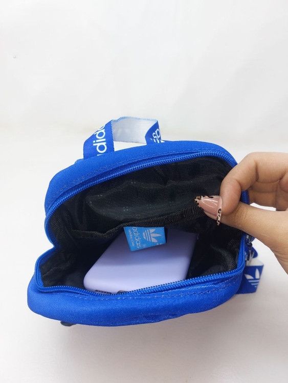 بادی بگ آبی آدیداس با زیپ مشکی و بند برنددار،نمایش فضای داخلی و کارت برند آدیداس – مناسب برای حمل وسایل شخصی روزمره