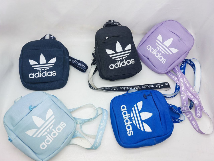 بادی بگ آدیداس با لوگوی سفید و بند برنددار، در رنگهای مشکی، یاسی، آبی روشن، سرمهای و آبی سلطنتی – مناسب برای استفاده روزمره و استایل اسپرت